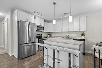 A kitchen with white cabinets and a marble countertop.